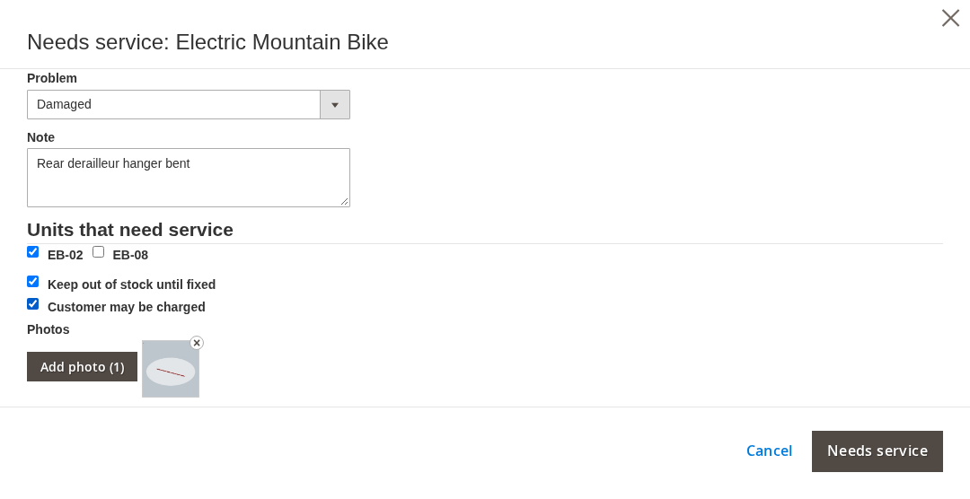 The Return Rentals grid with the Needs service box open for an electric mountain bike, unit EB-02 ticked, the problem Damaged, the note Rear derailleur hanger bent, one photo added, and Keep out of stock until fixed and Customer may be charged ticked